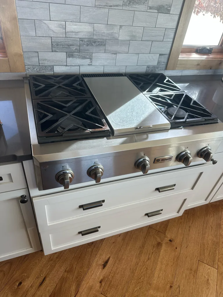 GE Cafe gas rangetop with a griddle in a white kitchen