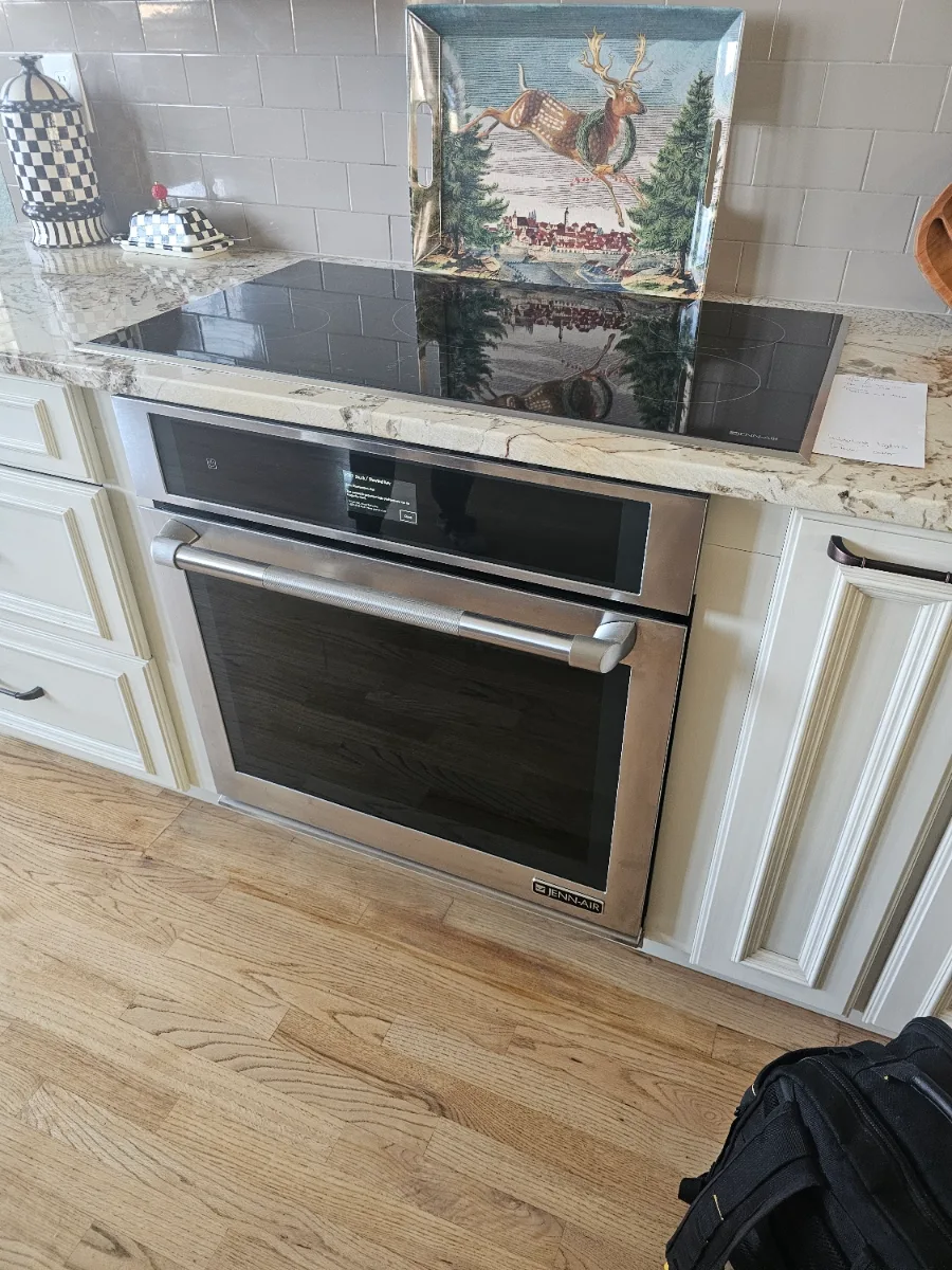 JennAir range with a glass cooktop under a decorative backsplash