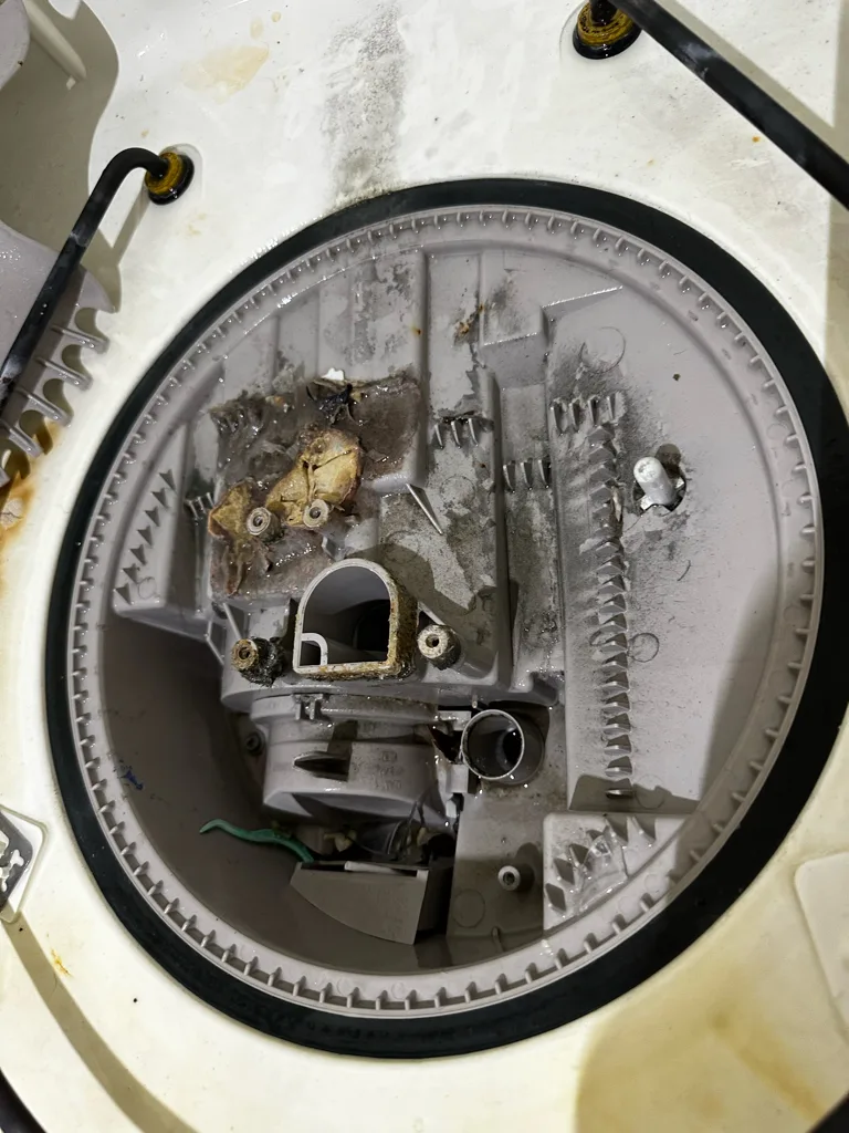 Sump and filter area of a Kenmore dishwasher with debris around the pump