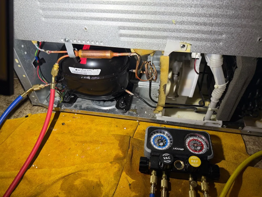 Refrigerant gauges connected during a Kenmore refrigerator compressor replacement
