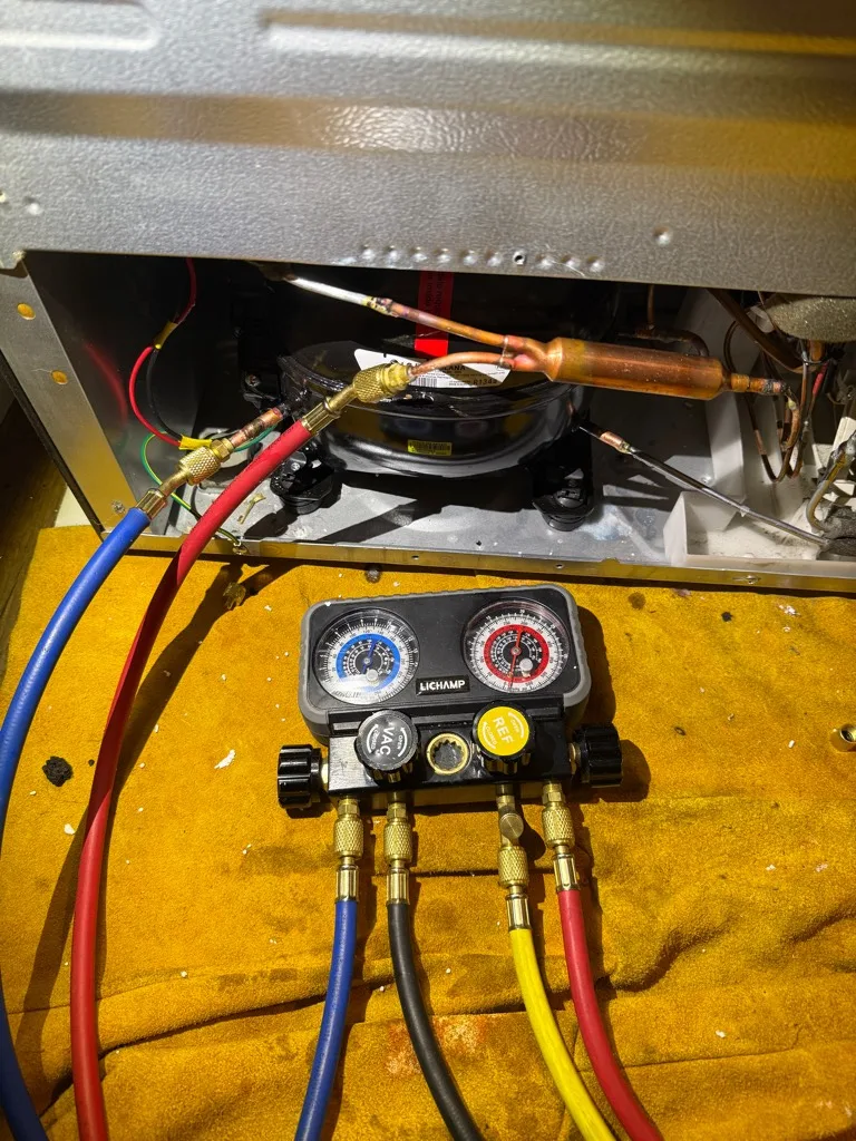 Refrigeration gauges connected during an LG refrigerator compressor replacement