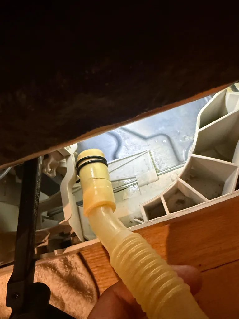 Drain hose connection behind a Miele dishwasher