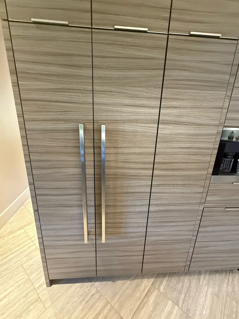 Miele built-in refrigerator and freezer columns behind wood-grain panels