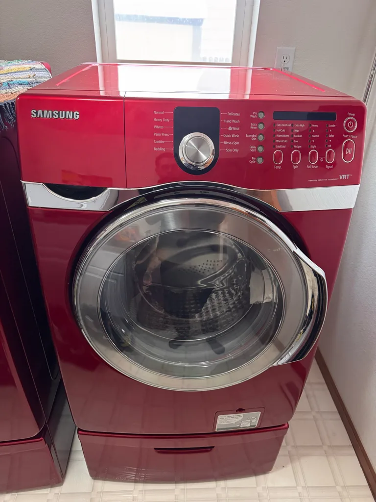 Red Samsung front-load washer on a pedestal before drain diagnosis