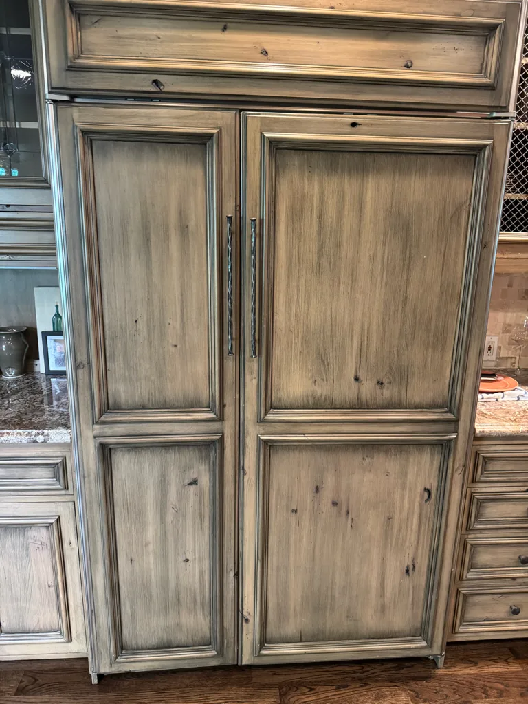 Panel-ready Sub-Zero built-in refrigerator behind rustic wood cabinet panels